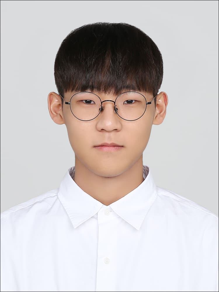 A young man with dark hair and round glasses wearing a white button-down shirt.